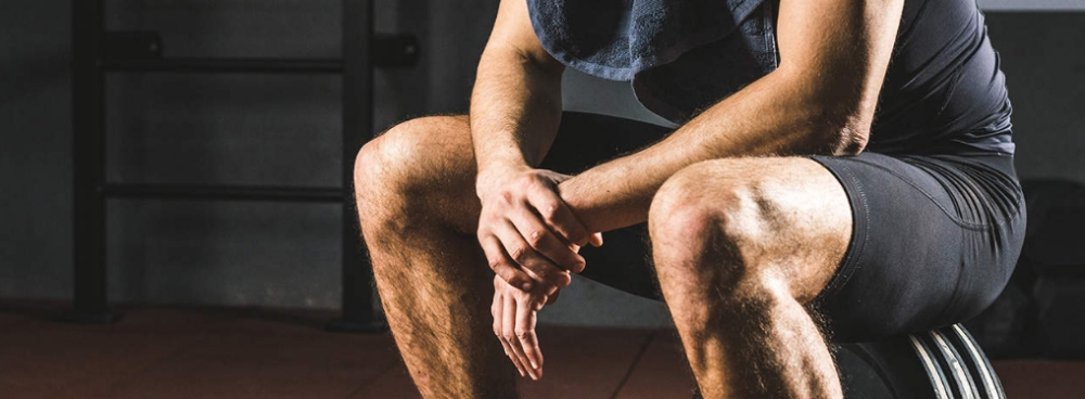 Man after exercise sitting on weights