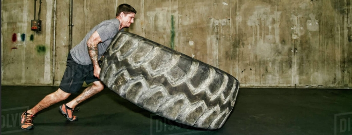 Man lifting tire in gym.